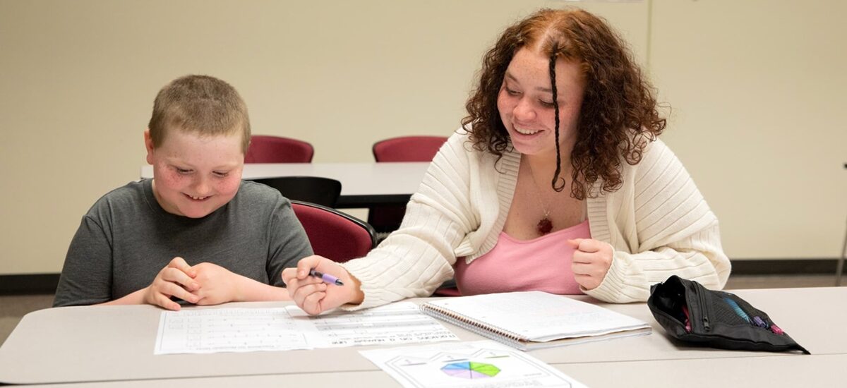 Graduate of master's in special education program working with a student in an inclusive classroom.