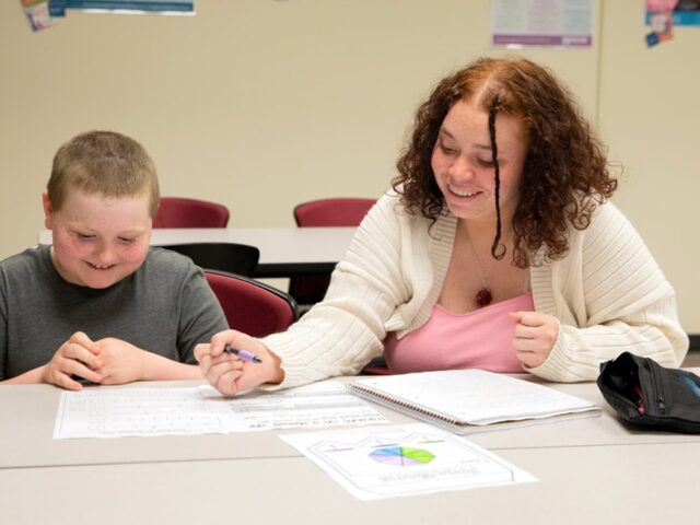 Graduate of master's in special education program working with a student in an inclusive classroom.