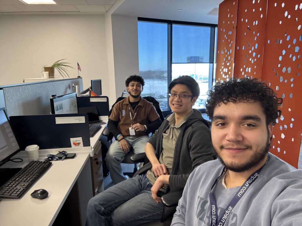 A Rowan information systems & analytics intern provided photo of Preet and two fellow interns sitting at a row of desks in the Subaru of America headquarters office. 