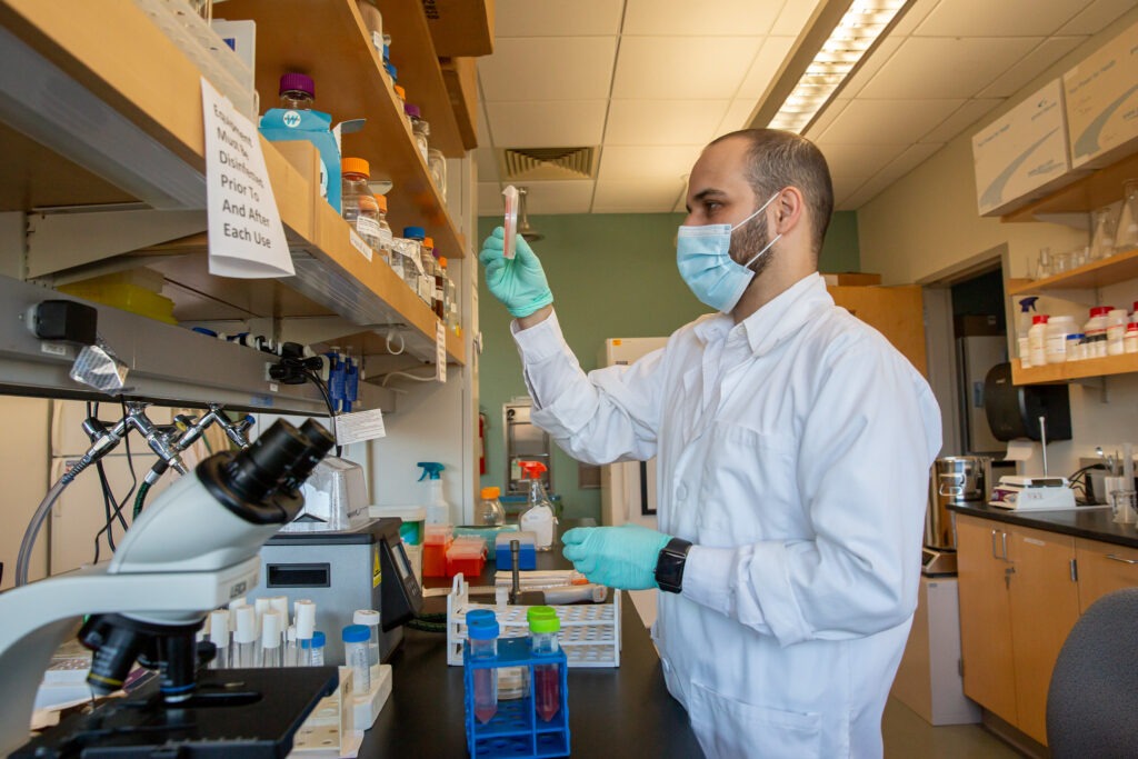 Pharmaceutical sciences master's student Omar peers at something he took off a shelf in a lab. 