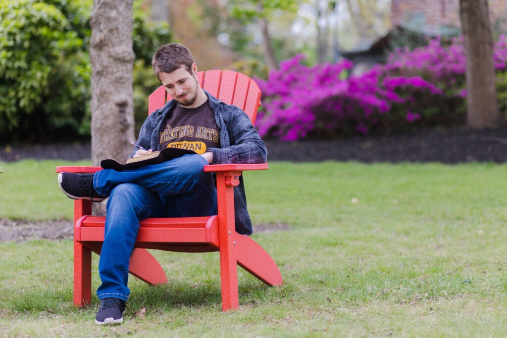 Student completing work for a summer course outside in chair.