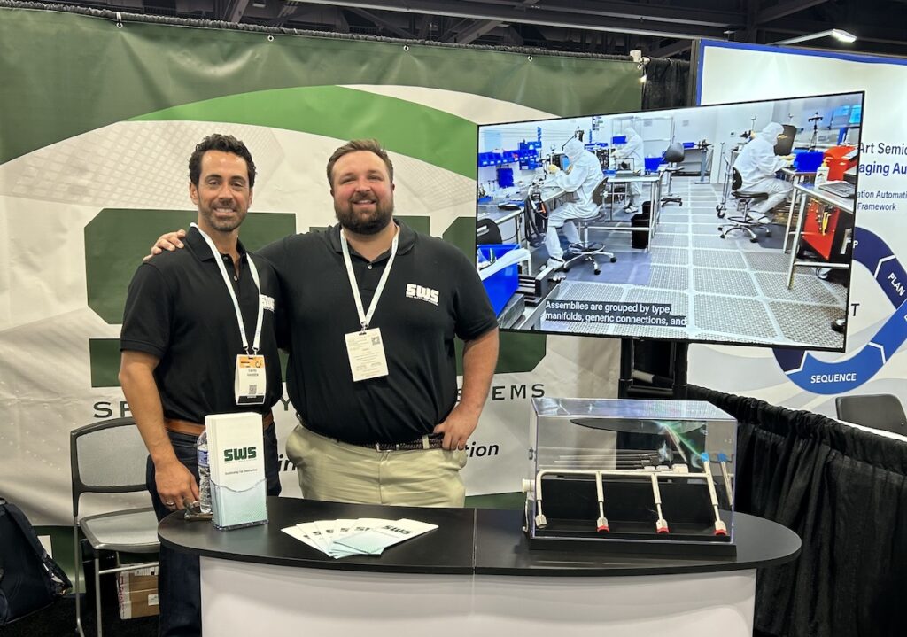 Rowan construction management program grad Autie stands at a trade booth representing his construction company, shoulder to shoulder with a colleague. 