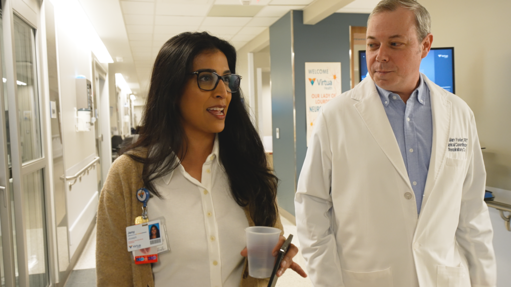 Online respiratory therapy student, Bill Y., mentoring his team member through a hallway discussion.