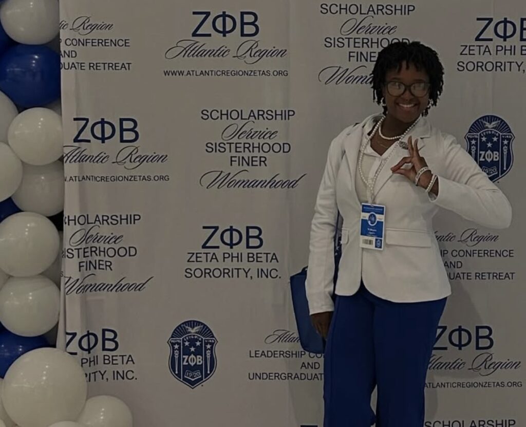 Rowan chemistry major Layahna poses in front of a Zeta Phi Beta Sorority, Inc. backdrop at an event. 