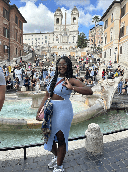 Rowan chemistry major Layahna poses for a tourist portrait in Rome with a fountain and a building behind her. 