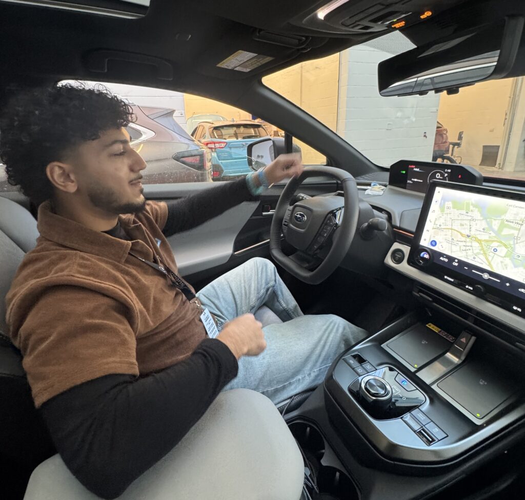 A Rowan information systems & analytics intern provided photo of Preet sitting inside a test car at Subaru of America headquarters, looking at the digital screen he is evaluating.  