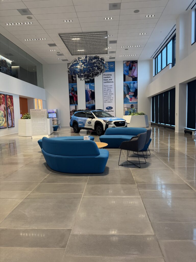 A Rowan information systems & analytics intern provided photo of the elegant, spacious and welcoming feeling of the lobby of Subaru of America headquarters, with a Subaru car prominently on display. 