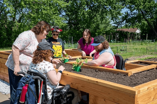 Rowan students work together around an accessible raised garden bed. 