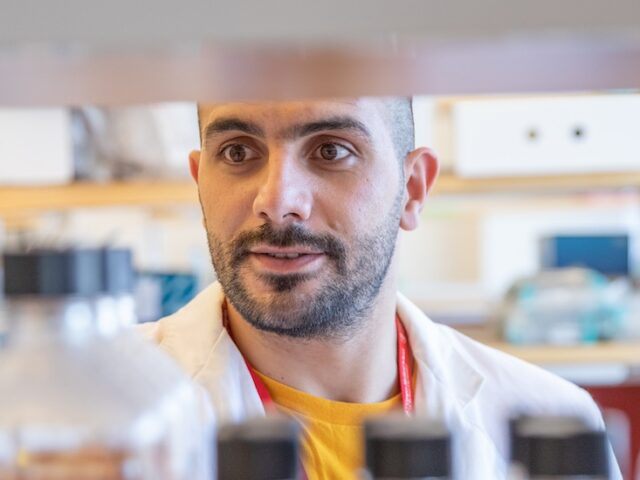 Pharmaceutical sciences master's student Omar chooses a bottle off of a shelf.