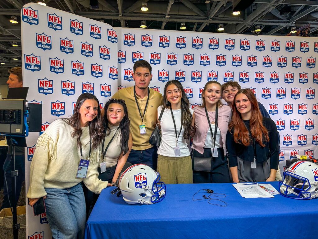 Six Rowan University sports communication & media majors pose at the NFL Alumni table during Super Bowl week. 