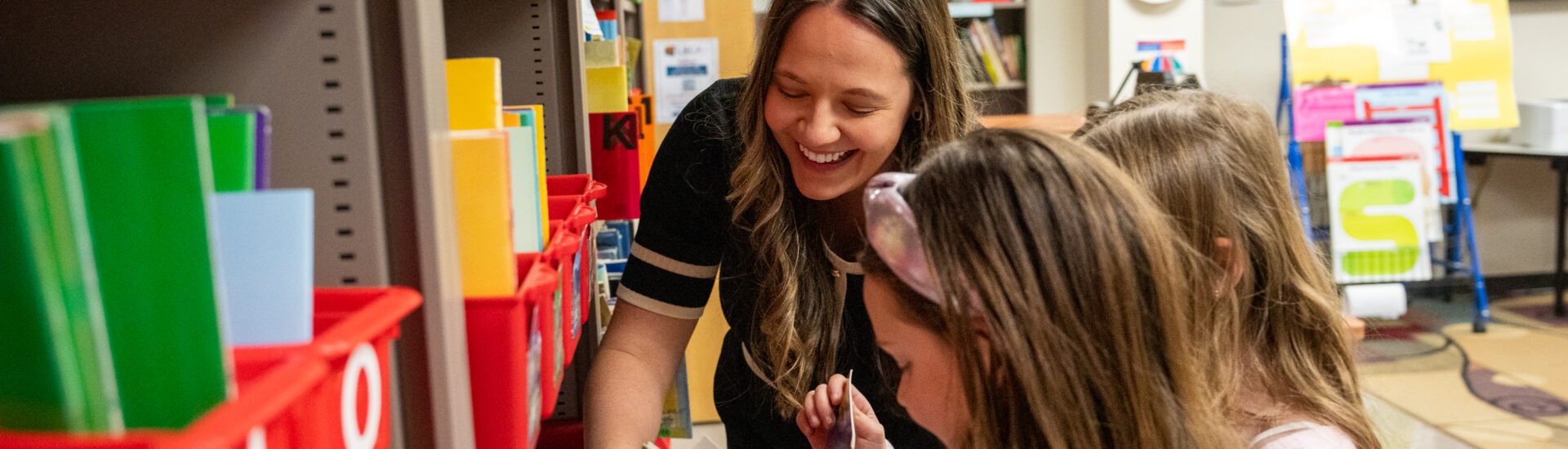 Kaitlyn G., graduate of Rowan's MA in Reading program, exploring books in the Reading Clinic with two students.