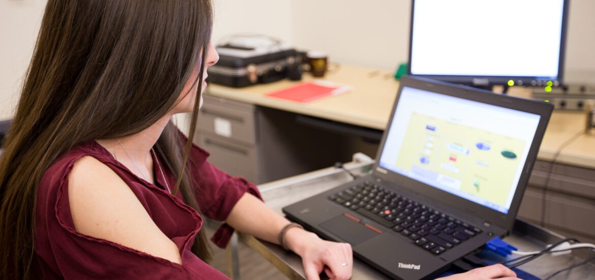 Female student using a laptop and computer software during a hands-on technology learning activity.