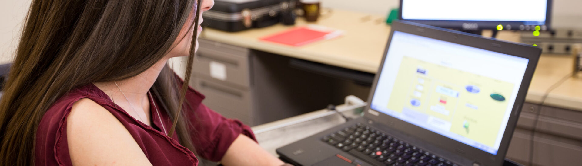 Female student using a laptop and computer software during a hands-on technology learning activity.