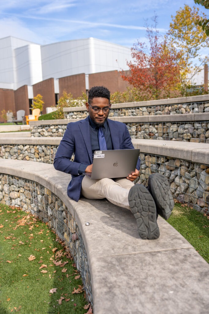 Shawn B., Rowan Online student dressed in suit completing program coursework outside.
