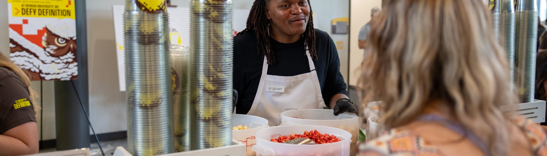 Tashir B., in action., with students serving his popcorn blend from his small business, The Ballard Bakery.