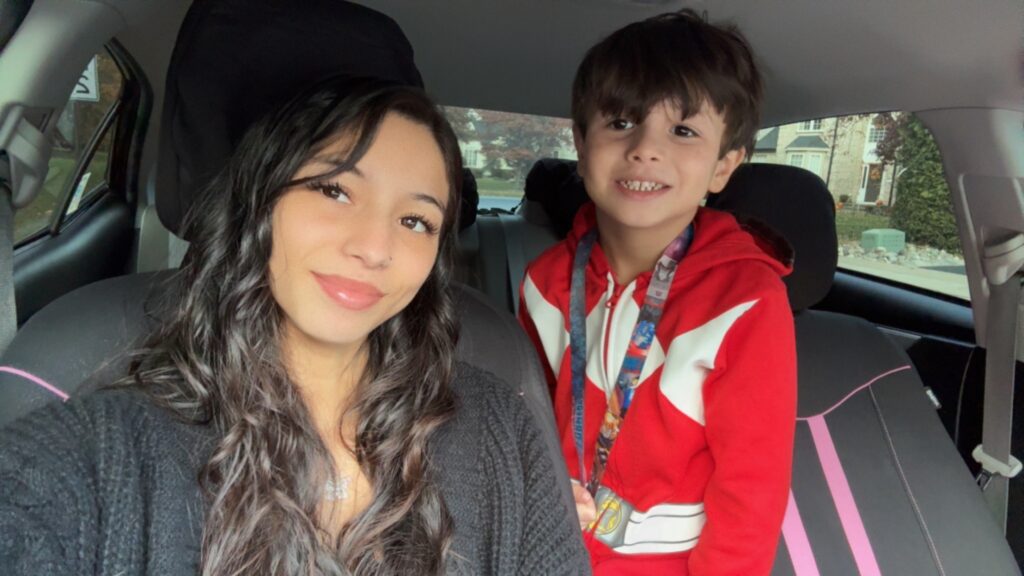 Rowan University senior and mom Kaitlyn A. poses for a selfie in the front seat of her car, with her six-year-old son beside her. 