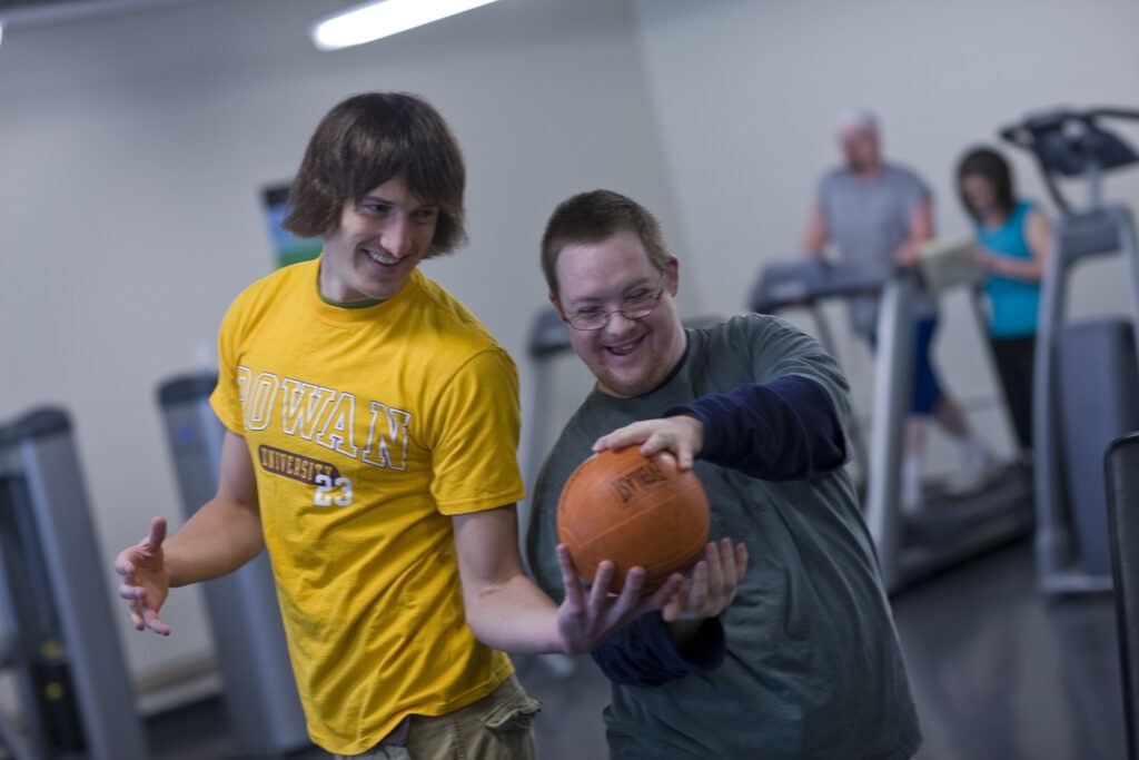 A Rowan University education major and aspiring physical education teacher engages in cardio with a person in the Fitness Center by passing a weighted ball to one another.