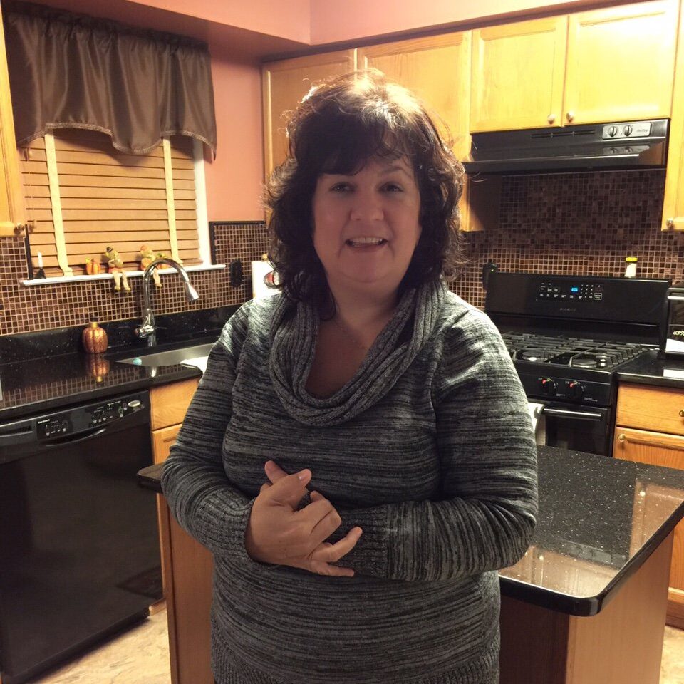 Mom Maria stands in her kitchen.