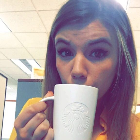 student sips coffee while studying at her internship