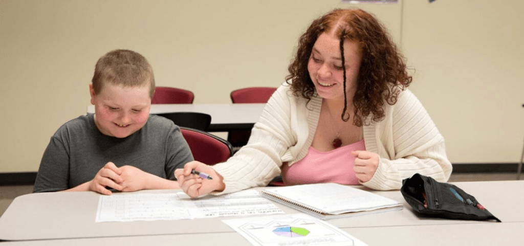 Special ed teacher in Rowan's online master's program working with a student in a classroom setting.