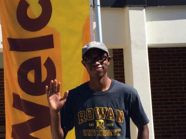 Rowan Choice student Davon waves while standing in front of a welcome banner
