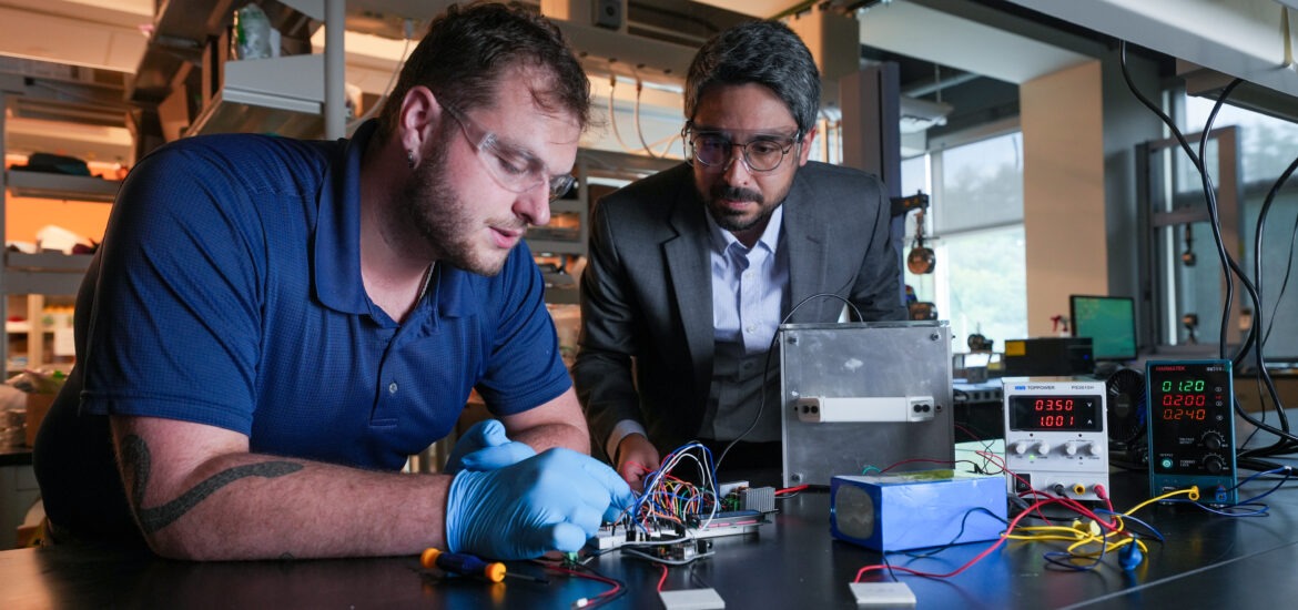 Engineering student and faculty member work together on an electronics project with wires, testing equipment and power supplies in a lab.