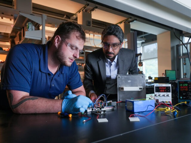 Engineering student and faculty member work together on an electronics project with wires, testing equipment and power supplies in a lab.