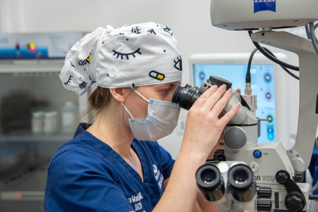 In the operating room, Dr. Mancuso peers into a microscope to get a better view.